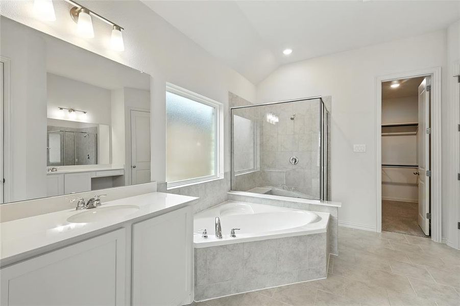 Bathroom featuring a shower stall, a walk in closet, a bath, vanity, and lofted ceiling