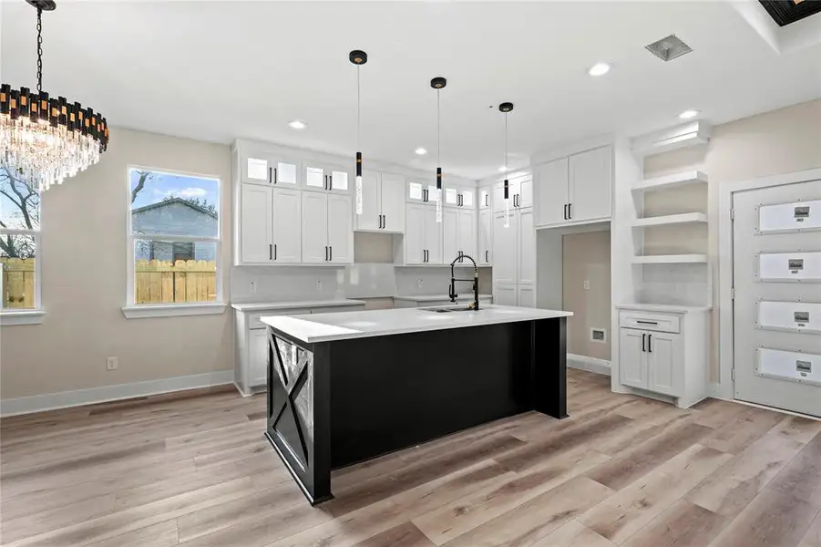 Kitchen with white cabinets, sink, a kitchen island with sink, and tasteful backsplash