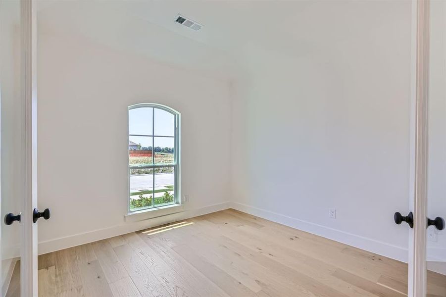 Empty room with french doors, light wood-style floors, and baseboards Empty room with french doors, light wood-style floors, and baseboards
