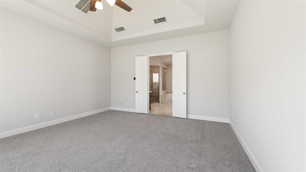 Spare room featuring ceiling fan, a raised ceiling, and carpet flooring