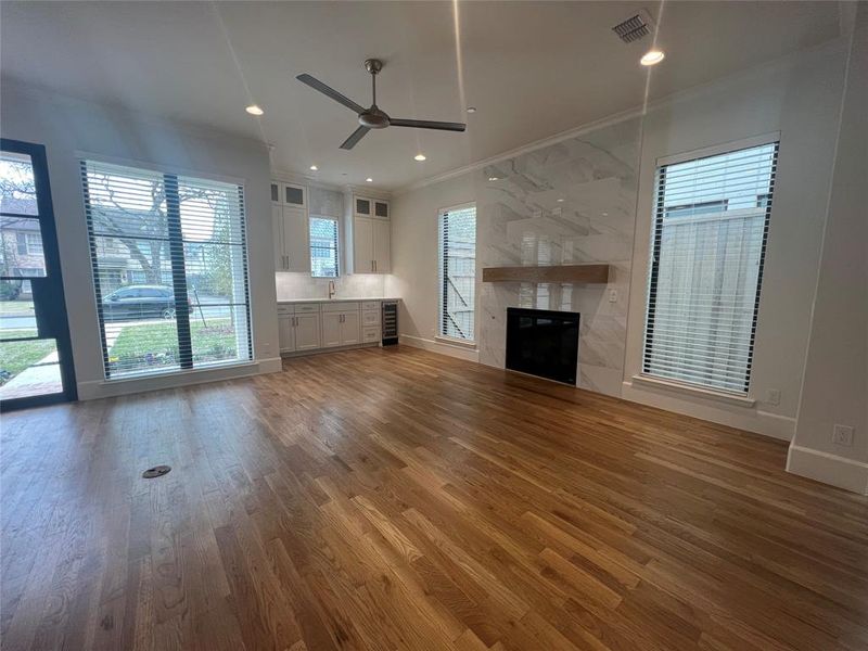 Unfurnished living room featuring ceiling fan, crown molding, hardwood / wood-style flooring, and a premium fireplace