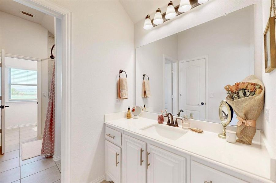 Bathroom featuring light tile patterned floors, vanity, and a shower with shower curtain