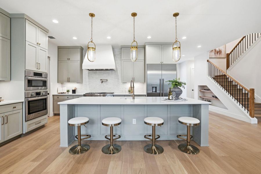 Kitchen with gray cabinets, hanging light fixtures, a kitchen bar, and a large island