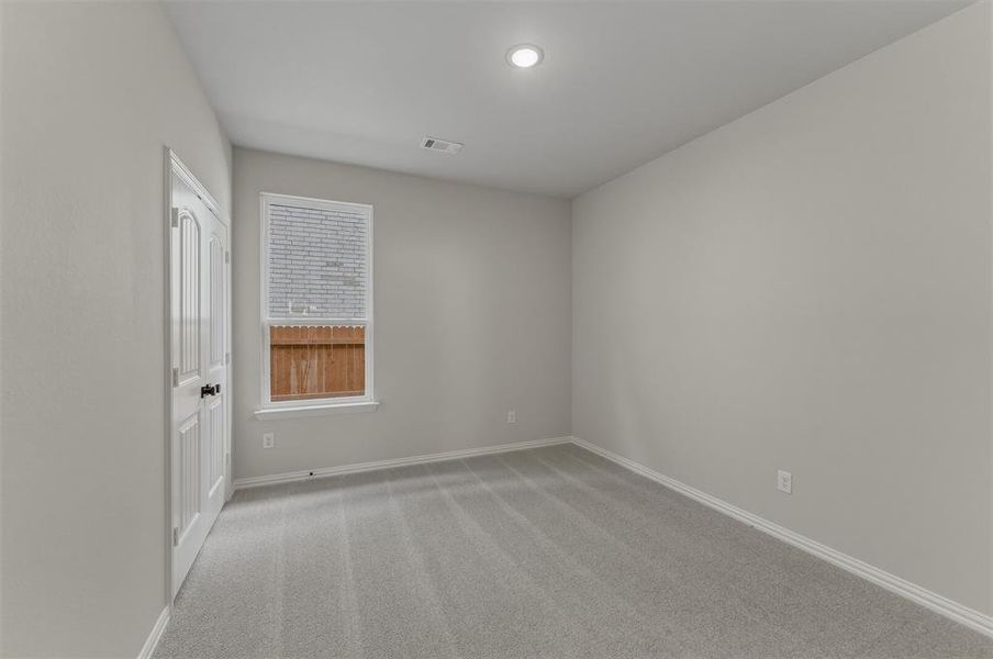 Carpeted room featuring a single window with blinds, white trim, recessed lighting, and a paneled door with black hardware