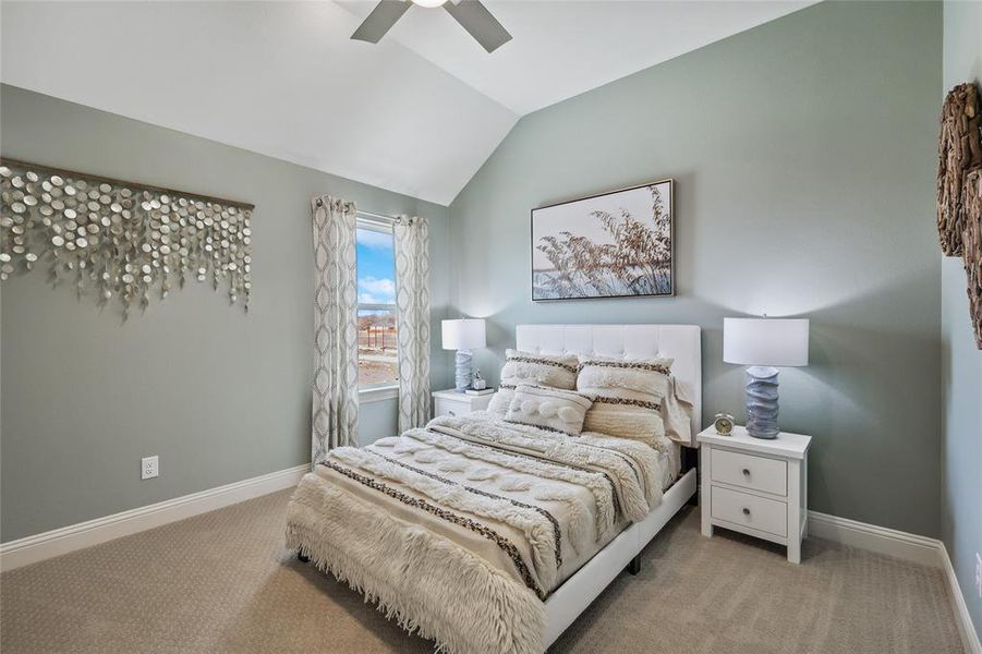 Carpeted room featuring a vaulted ceiling with a ceiling fan, a window with curtains, and two-drawer nightstands