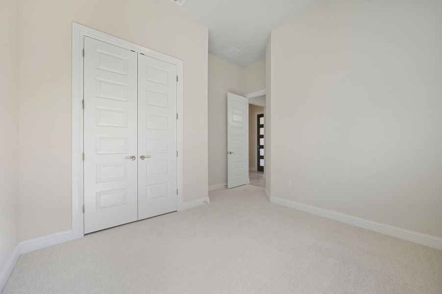 Unfurnished bedroom with light carpet and a closet Unfurnished bedroom with light carpet and a closet