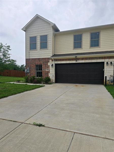 View of front of home with driveway, an attached garage, and brick siding