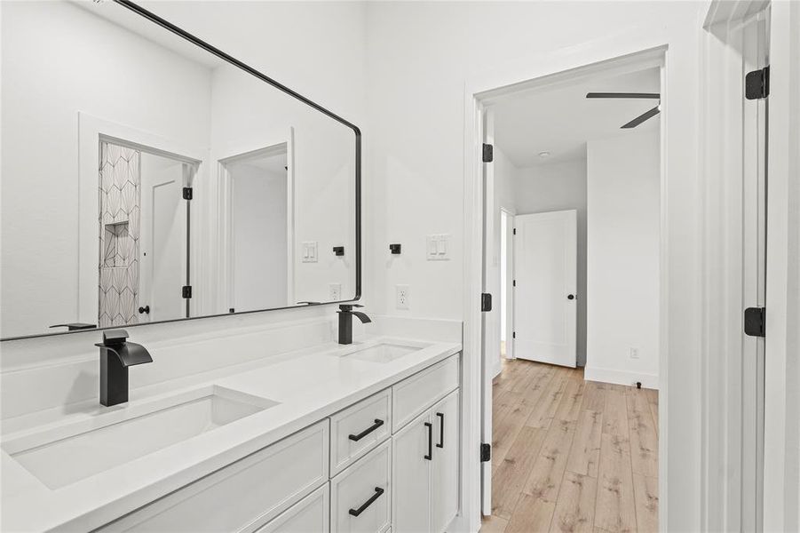 Full bathroom with double vanity and light wood-style flooring