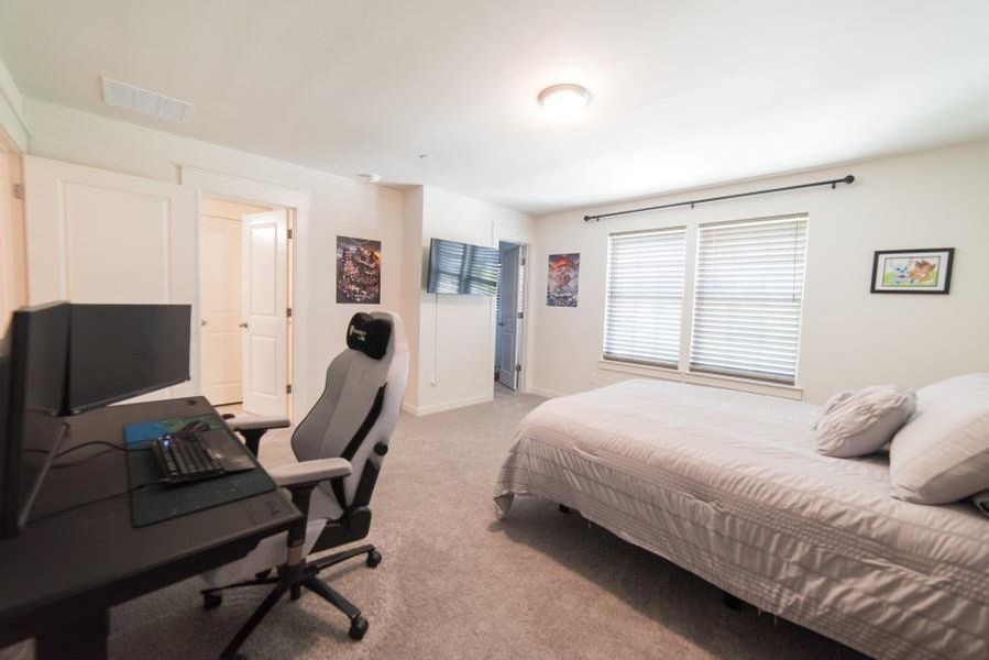 Bedroom with light carpet and an office area