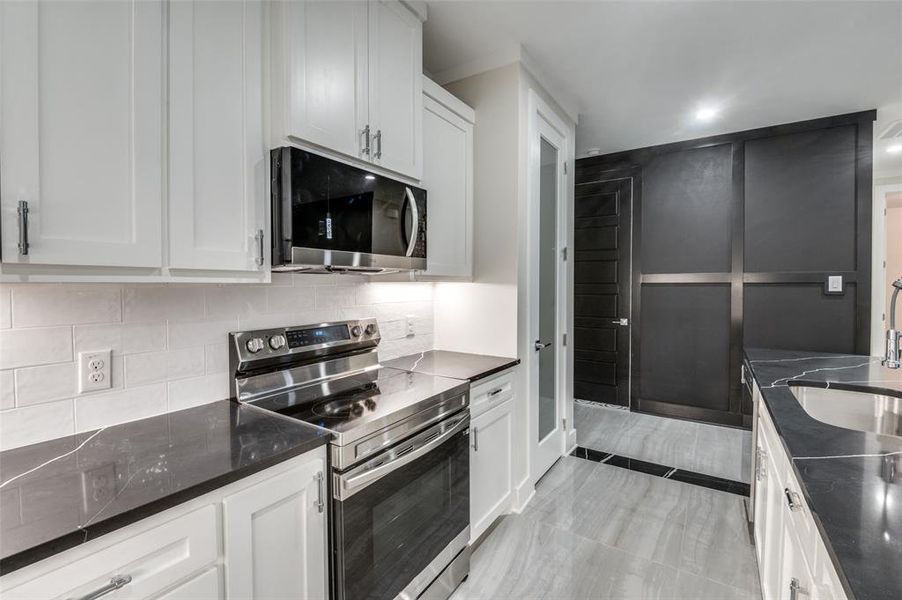 Kitchen with decorative backsplash, stainless steel appliances with stainless steel finishes, and white real wood cabinets