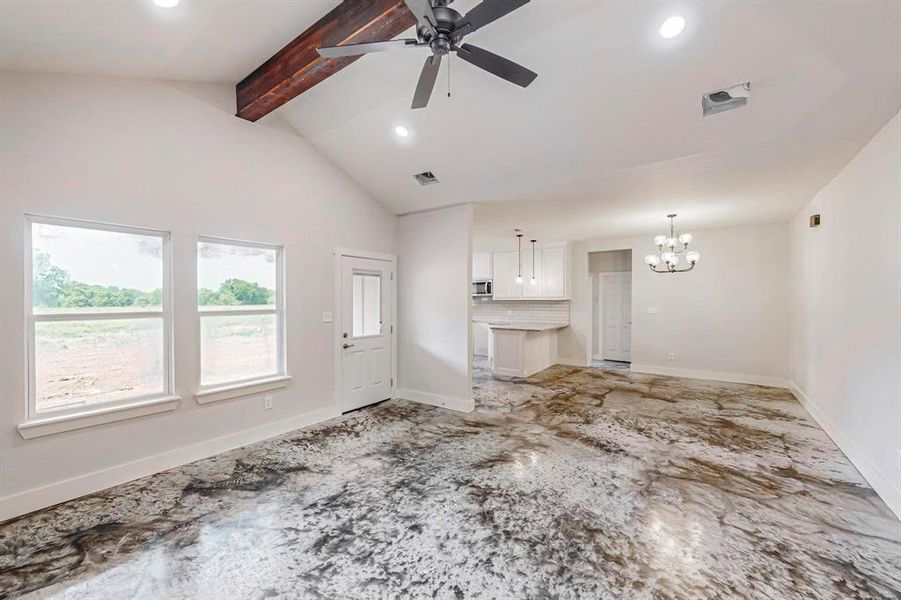 Unfurnished living room with vaulted ceiling with beams and ceiling fan with notable chandelier