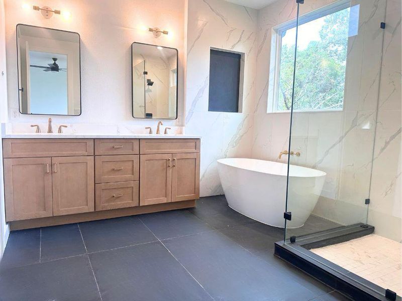 Elegant bathroom features a modern freestanding tub, a spacious glass-enclosed shower, and a dual vanity with sleek countertops. Elegant bathroom features a modern freestanding tub, a spacious glass-enclosed shower, and a dual vanity with sleek countertops.
