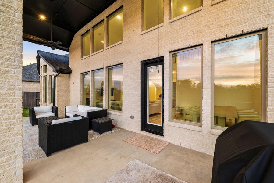 Rear exterior view highlighting the covered patio and expansive windows that enhance indoor-outdoor living.