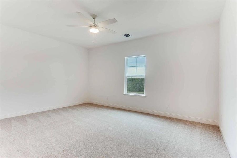 Spare room with light carpet and a ceiling fan