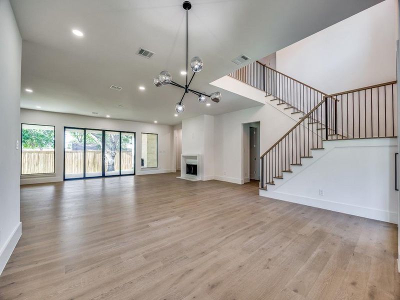 Unfurnished living room with light wood-type flooring and an inviting chandelier