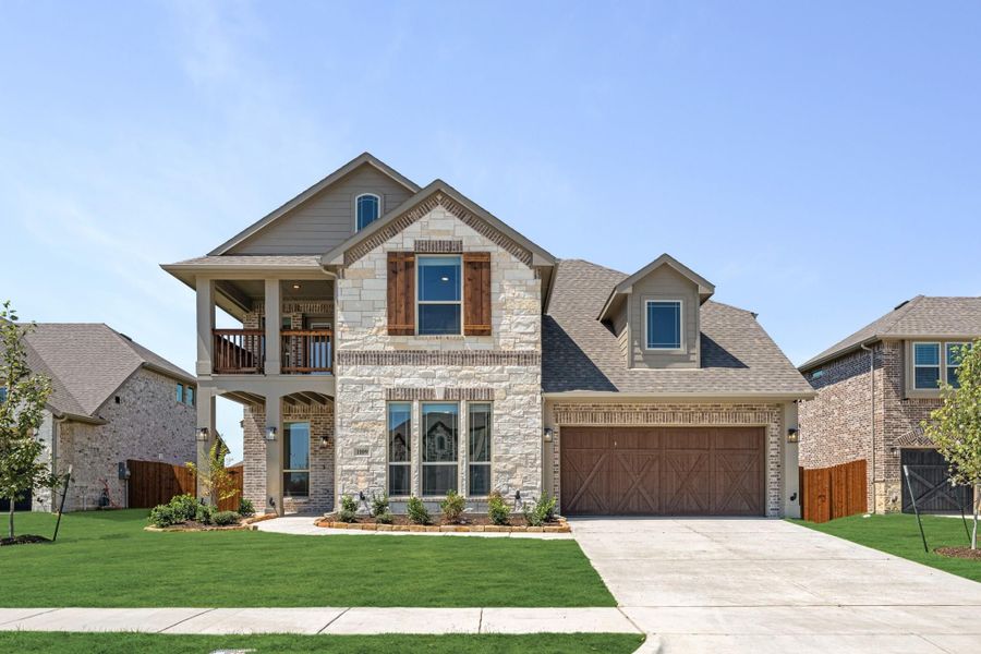 Two-story home with stone and brick exterior, second-floor balcony, and two-car garage Two-story home with stone and brick exterior, second-floor balcony, and two-car garage