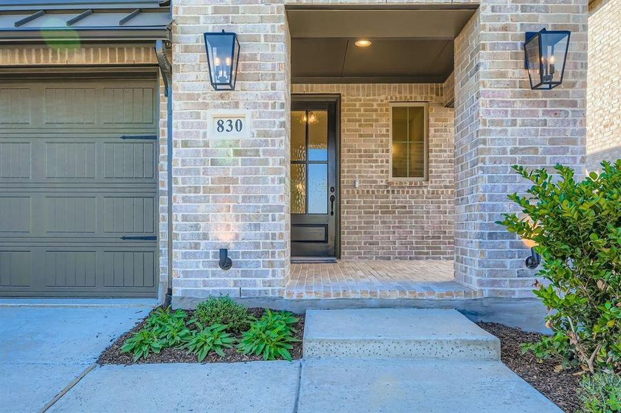 Entrance to property featuring covered porch and brick siding