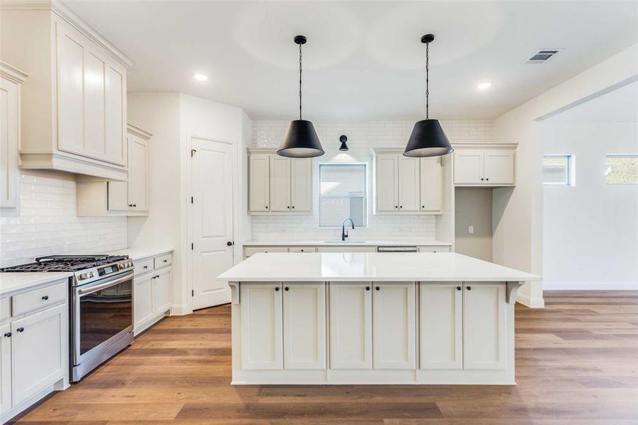 Kitchen featuring high end stove, light hardwood / wood-style flooring, a kitchen island, and sink