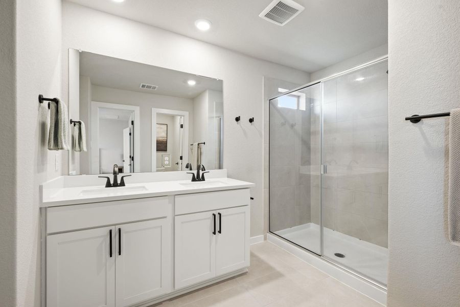 A contemporary dual vanity sits adjacent to a sleek glass-enclosed shower with custom tile surrounds. A contemporary dual vanity sits adjacent to a sleek glass-enclosed shower with custom tile surrounds.