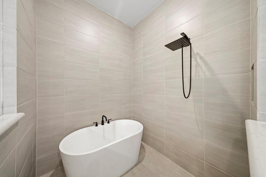 The primary bath showcases a spa-inspired wet room, seamlessly combining a freestanding soaking tub and spacious shower within one beautifully designed space for a luxurious, resort-like experience.