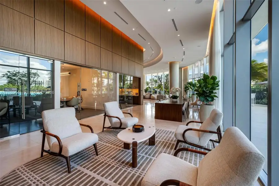 Floor-to-ceiling glass walls, wood-paneled wall accents, recessed lighting, curved architectural ceiling details, and polished stone flooring
