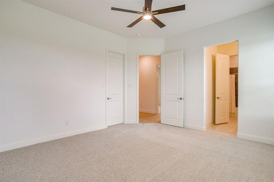 Secondary bedroom with ceiling fan and walk in closet