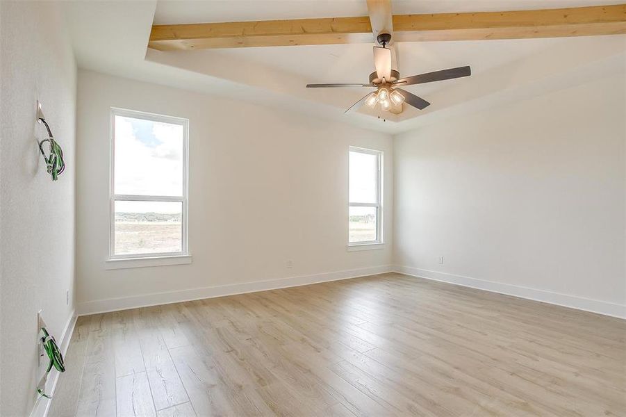 Spare room with beamed ceiling, light hardwood / wood-style flooring, and ceiling fan