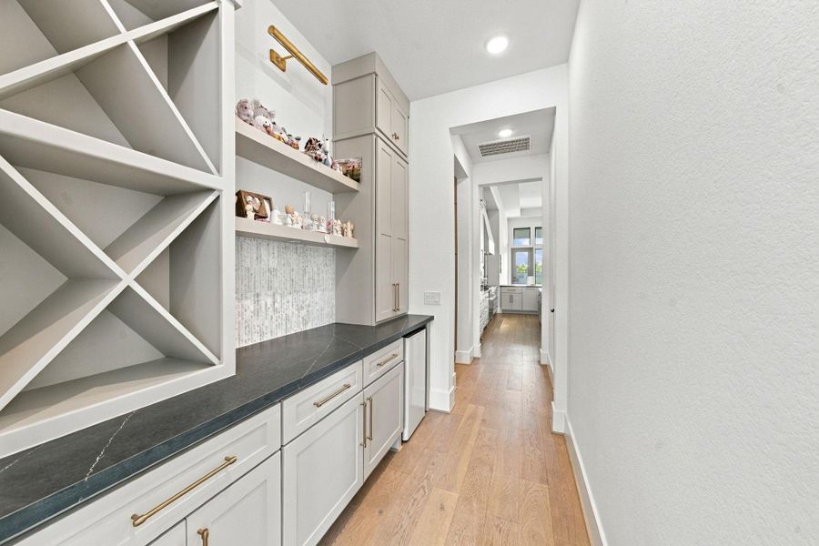 Connecting the formal dining room directly to the main kitchen, this functional butler's pantry offers built-in wine storage, open display shelving, and a built-in mini fridge.