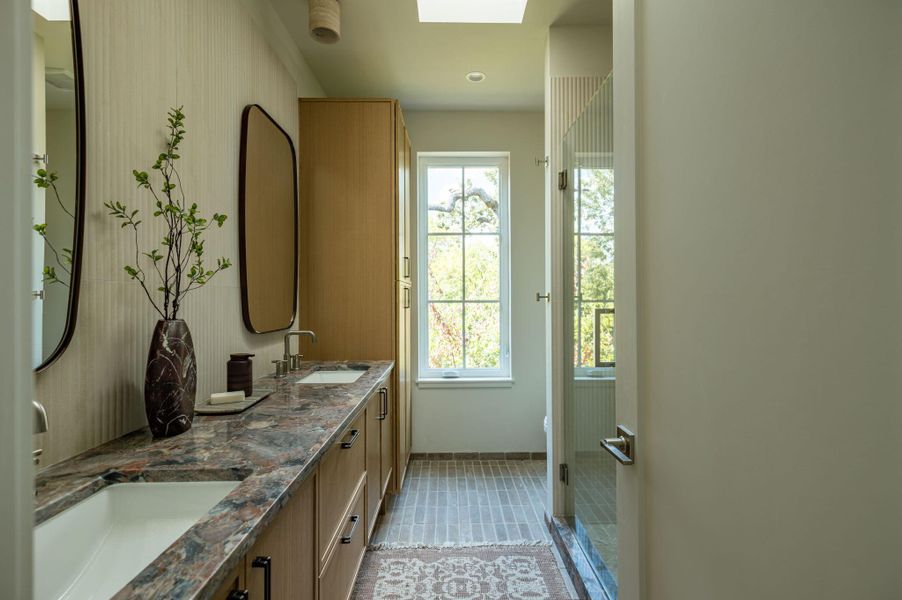 Exquisite stone countertops and sleek modern cabinetry anchor this beautifully lit bathroom space. Exquisite stone countertops and sleek modern cabinetry anchor this beautifully lit bathroom space.