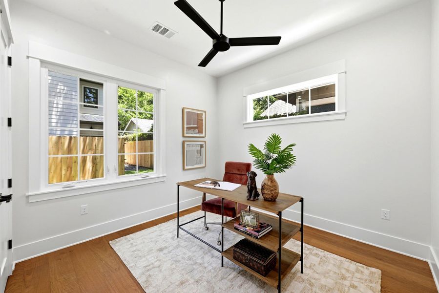 Well-lit study with wood floors and a contemporary ceiling fan offers a comfortable workspace. Well-lit study with wood floors and a contemporary ceiling fan offers a comfortable workspace.