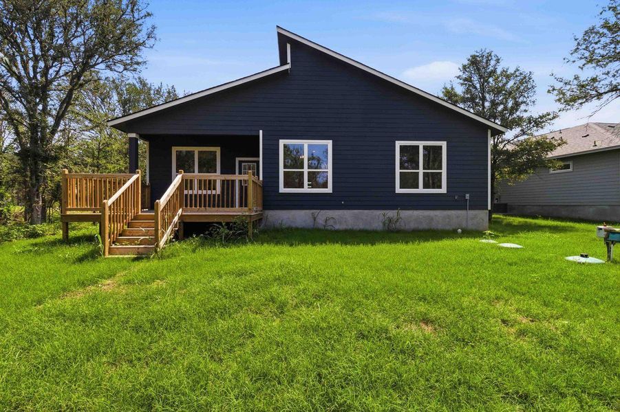 A dark-hued residence with a wooden deck overlooks a generous, well-kept lawn. A dark-hued residence with a wooden deck overlooks a generous, well-kept lawn.