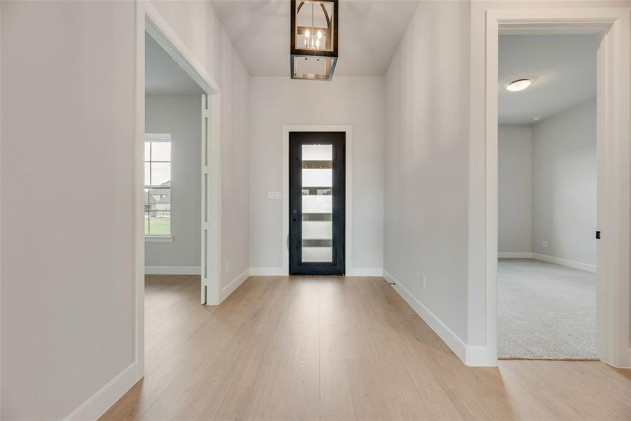Entrance foyer with light wood-style floors and a chandelier
