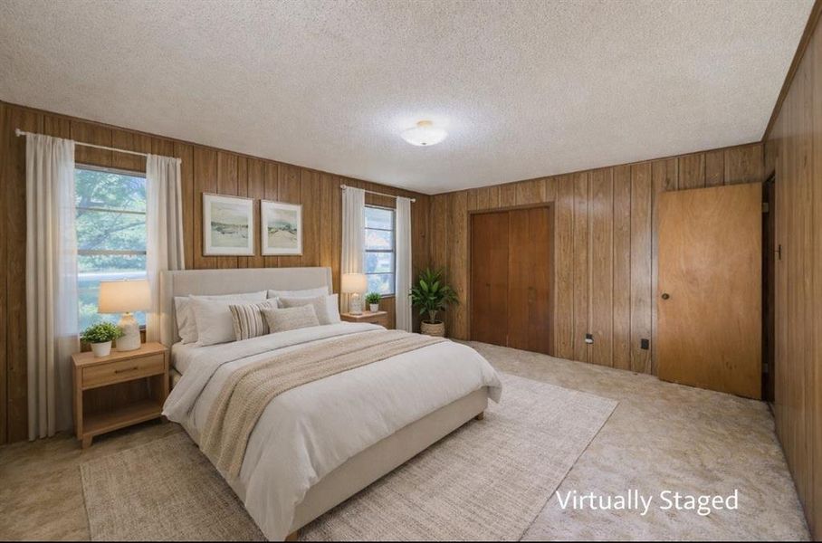 Bedroom featuring a closet, a textured ceiling, wood walls, and light colored carpet