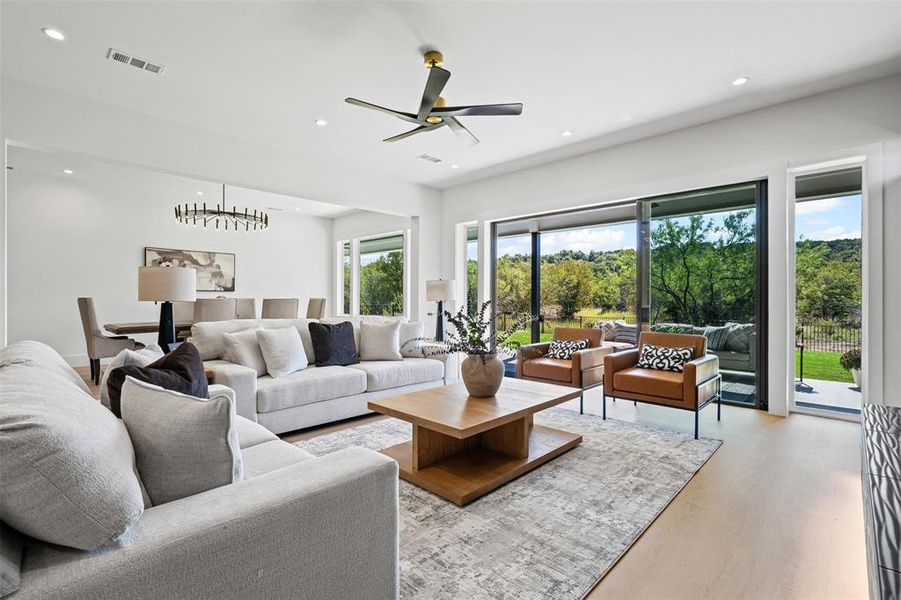 Living room featuring recessed lighting, light wood-type flooring, a ceiling fan, and a chandelier