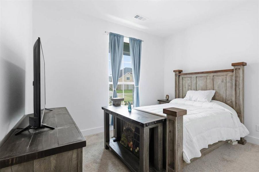 Bedroom featuring light neutral wall paint, carpet flooring, and a window with light blue curtains