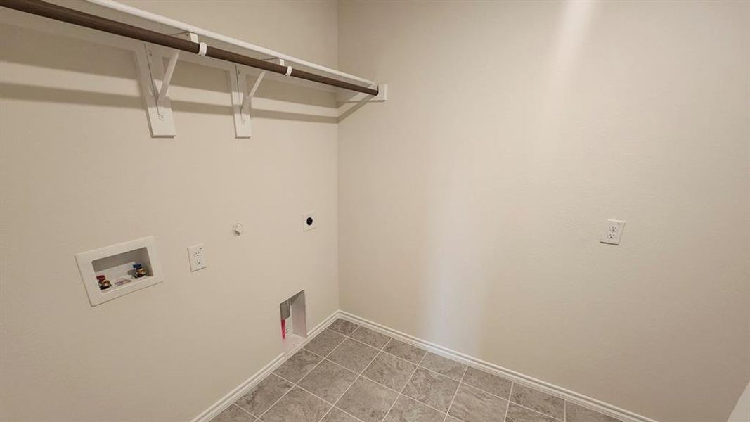 Utility area featuring a clothes hanging rod, tile flooring, and light neutral wall paint