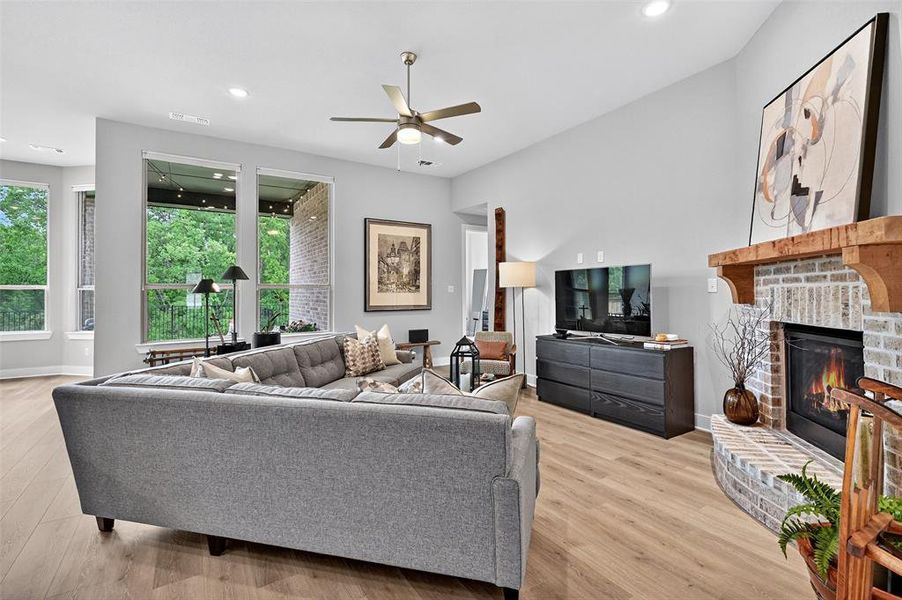 Living area with a ceiling fan, a brick fireplace, light wood-style floors, and recessed lighting Living area with a ceiling fan, a brick fireplace, light wood-style floors, and recessed lighting