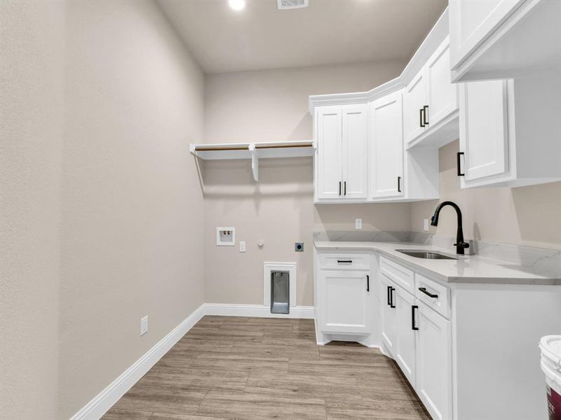 Laundry area with cabinets, hookup for a gas dryer, sink, hookup for an electric dryer, and light hardwood / wood-style floors