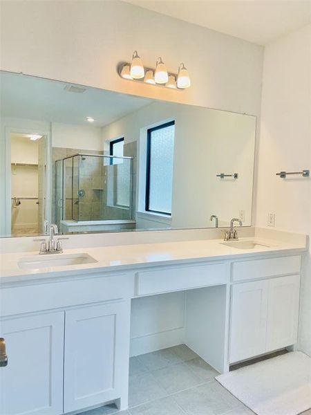 Full bath featuring a shower stall, double vanity, light tile patterned floors, and a spacious closet Full bath featuring a shower stall, double vanity, light tile patterned floors, and a spacious closet