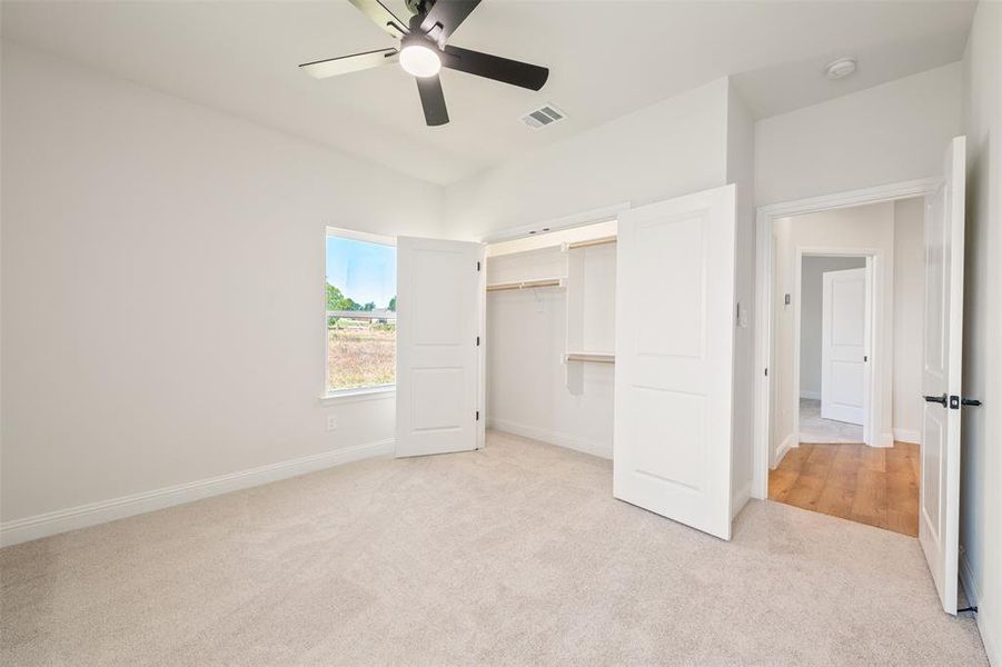 Unfurnished bedroom with light carpet, a ceiling fan, and a closet