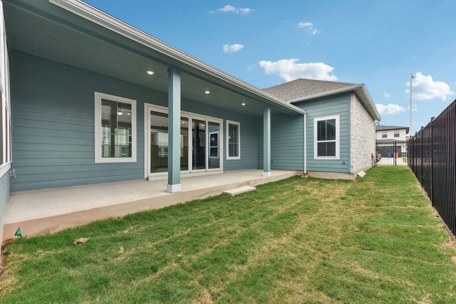 Expansive concrete patio beneath a covered porch, featuring recessed lighting and a ceiling fan