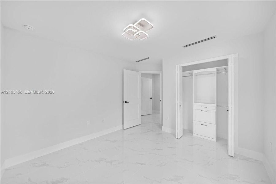 White tile flooring, contemporary ceiling light fixture, white interior doors, built-in closet organization system, recessed lighting White tile flooring, contemporary ceiling light fixture, white interior doors, built-in closet organization system, recessed lighting