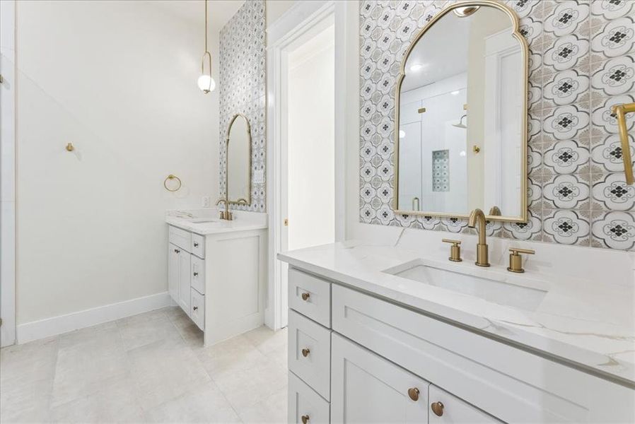 Bathroom featuring two vanities, a stall shower, and light tile patterned floors
