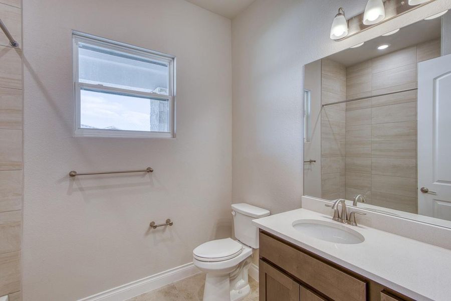 Bathroom with vanity, tiled shower, and tile patterned flooring