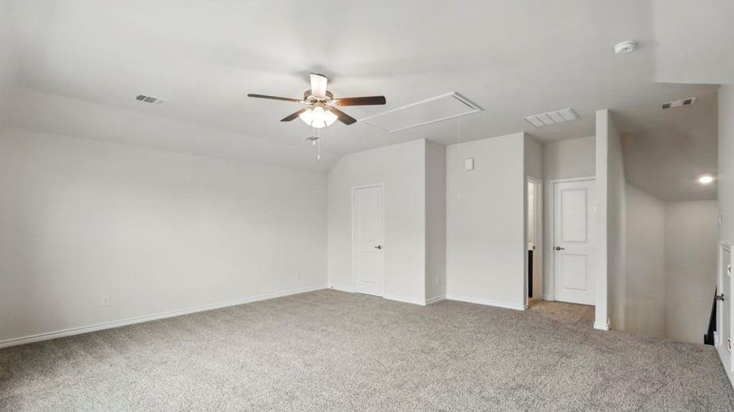 Carpeted room with a ceiling fan, white walls, and multiple doors