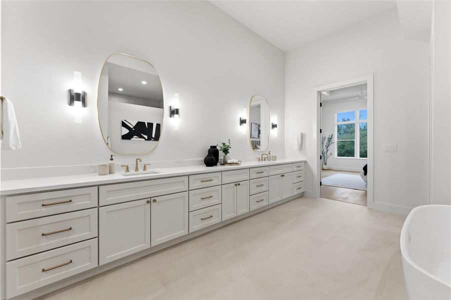 Full bath with double vanity, a freestanding bath, and light flooring