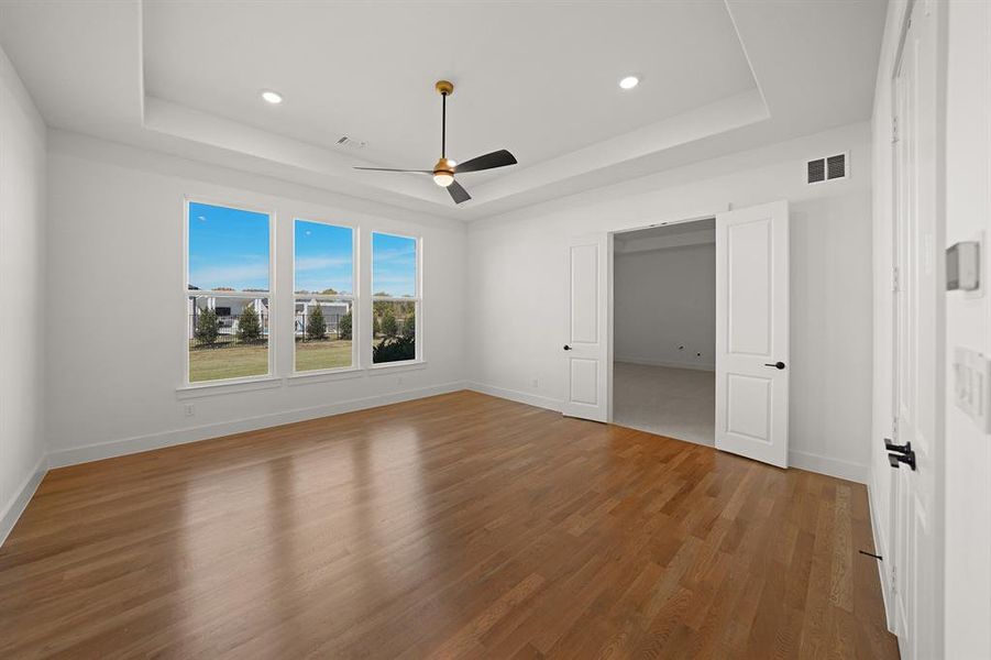 Unfurnished bedroom featuring a raised ceiling, light wood-type flooring, a ceiling fan, and recessed lighting Unfurnished bedroom featuring a raised ceiling, light wood-type flooring, a ceiling fan, and recessed lighting