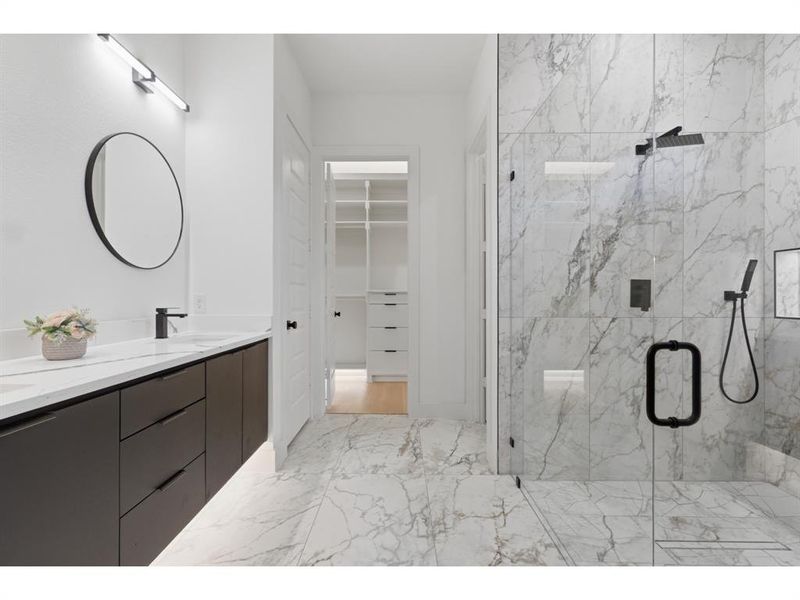 Contemporary bathroom featuring a spacious glass-enclosed shower with black fixtures and large format marble-look tile