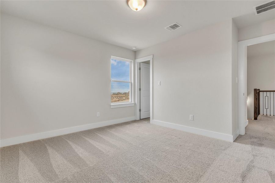 A quiet, carpeted room awaits personalization, bathed in natural light from a prominent window.