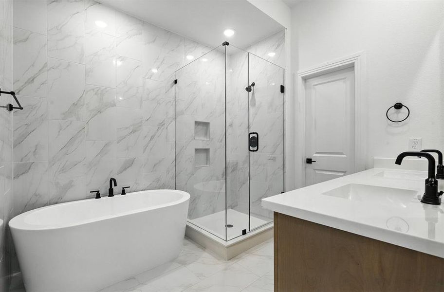 Full bathroom with a freestanding tub, light marble finish floors, a marble finish shower, double vanity, and tile walls Full bathroom with a freestanding tub, light marble finish floors, a marble finish shower, double vanity, and tile walls